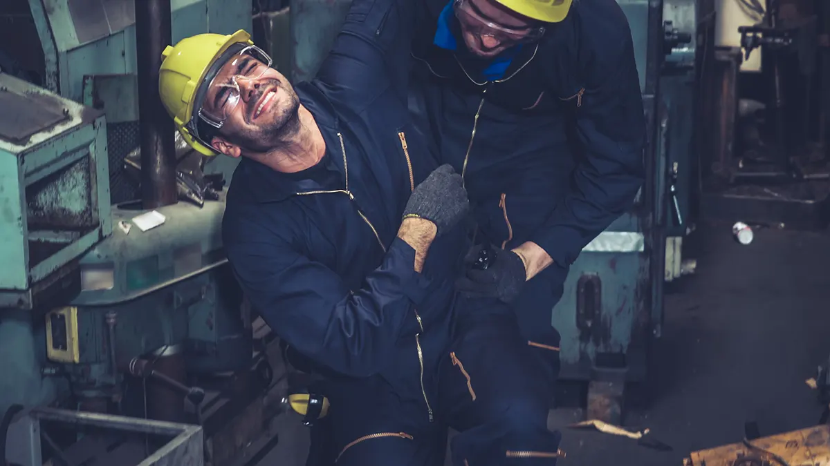 Factory worker helping an injured workmate