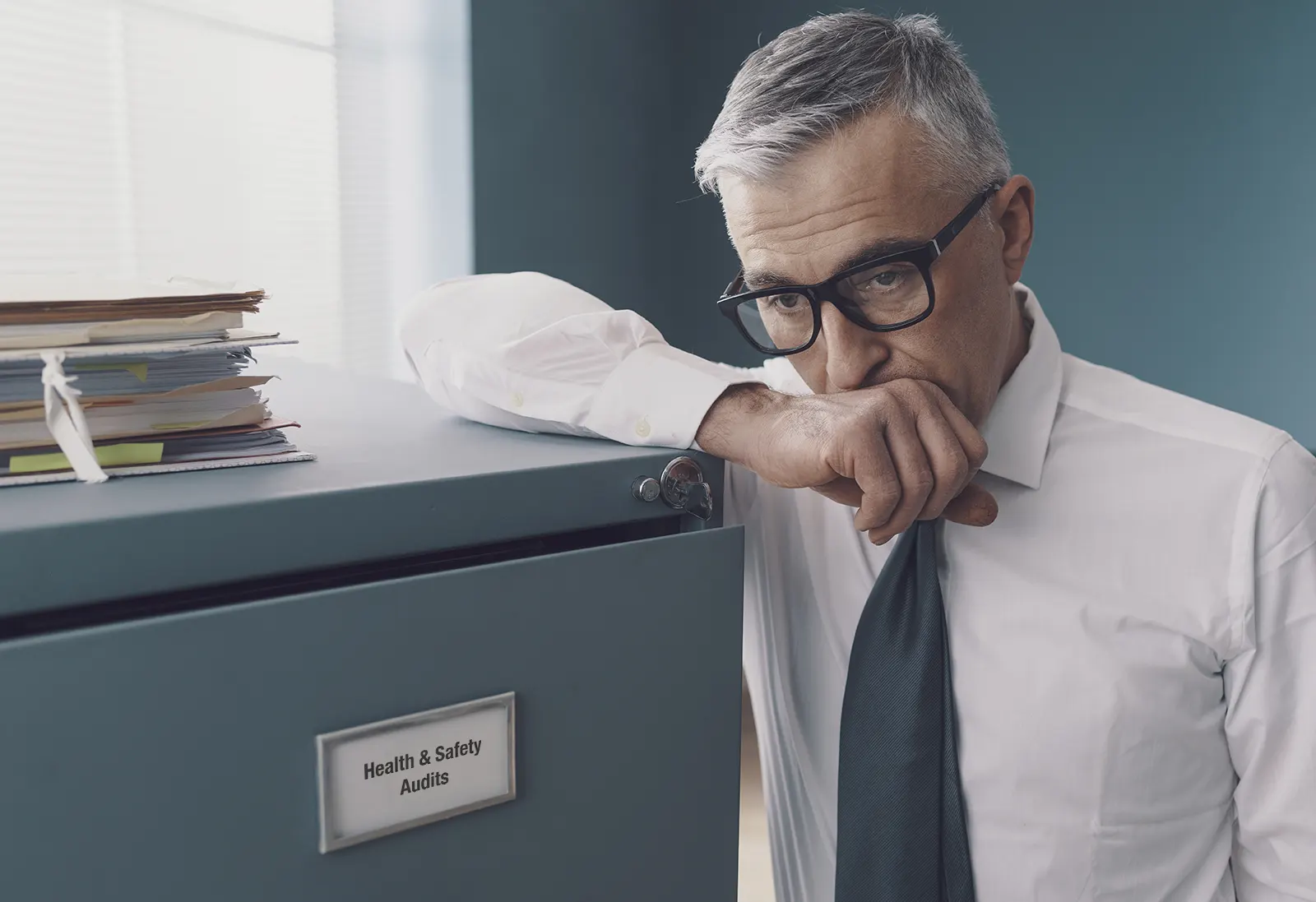 Businessman at filing cabinet worried about his health & safety records